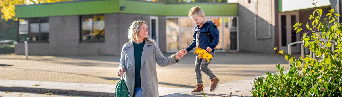 Moeder loopt hand in hand met haar zoontje voor een openbaar gebouw