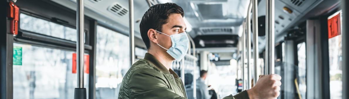 Een jonge man met een mondkapje staat in de tram