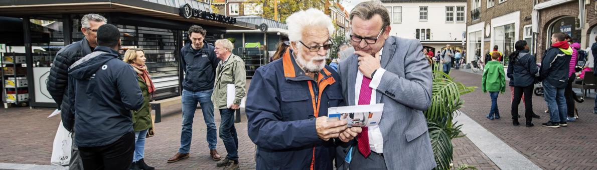 Reinier van Zutphen in gesprek met een oudere man tijdens de provincietour in Zeeland