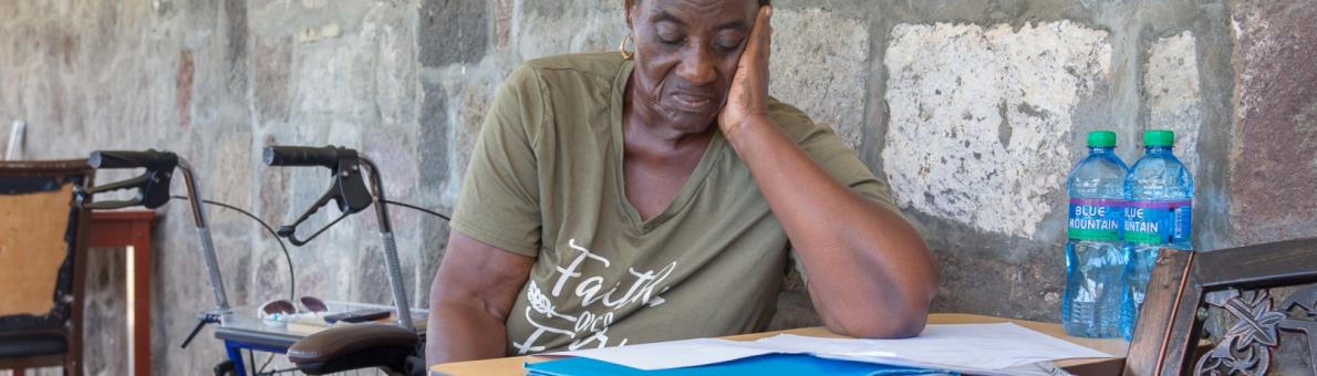 Caribische vrouw zit aan tafel en leest een brief