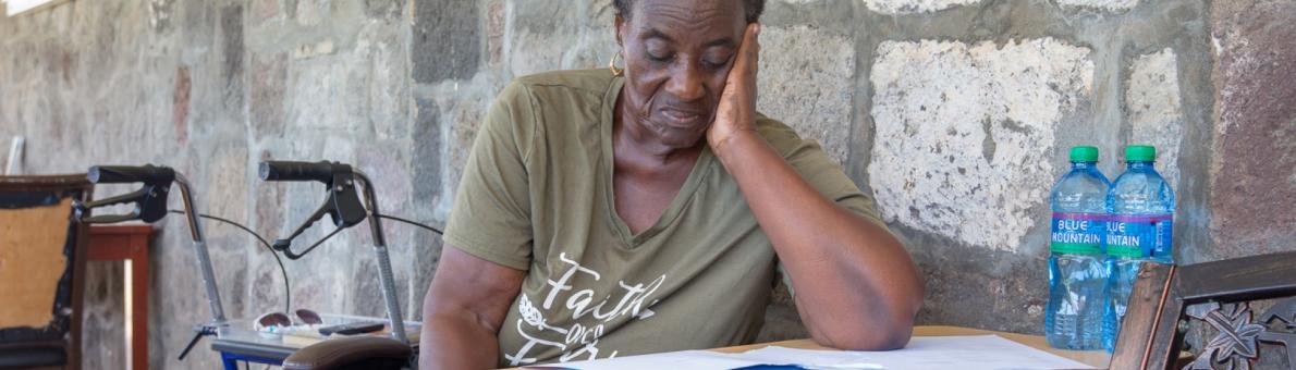 Caribische vrouw zit aan tafel en leest een brief