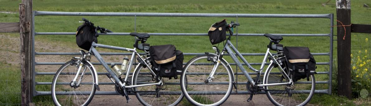 Twee fietsen tegen een hek bij weiland