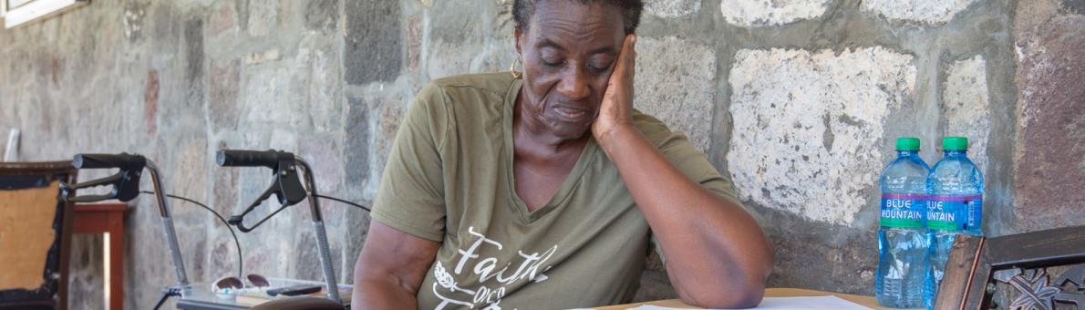 Vrouw zit aan tafel en leest document (Caribisch NL)