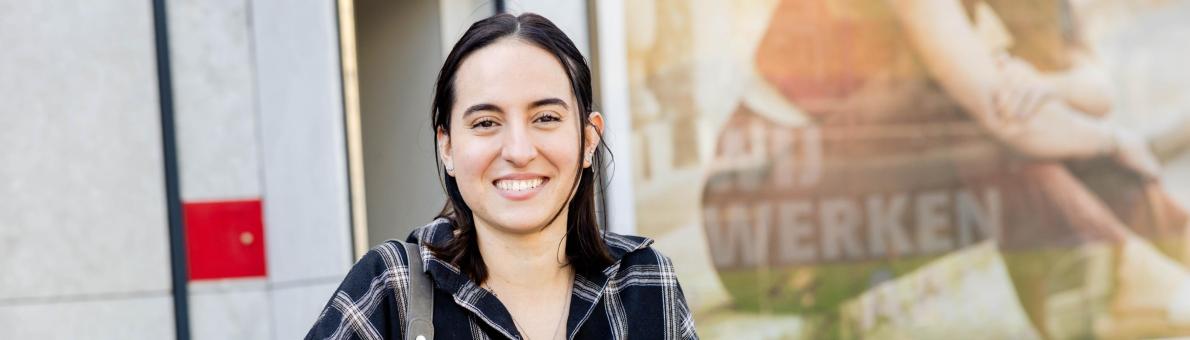 Sofia, een studente van 21 staat met haar fiets in haar hand. Ze heeft lang donkerbruin haar en glimlacht.