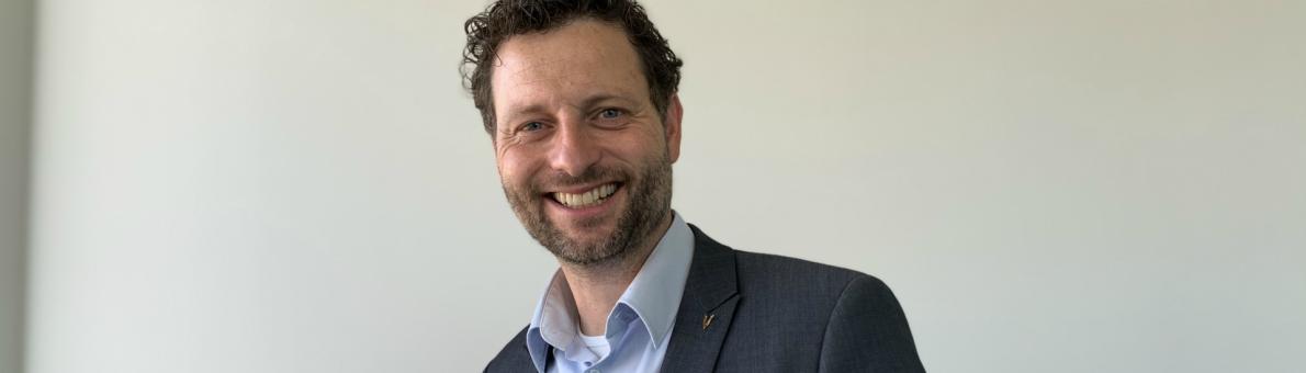 Lachende man (Matthijs van der Hoeven, coördinator Veteranenombudsman), donkere krullen, baard, draagt blauw overhemd en donker jasje Lachende man (Matthijs van der Hoeven, coördinator Veteranenombudsman), donkere krullen, baard, draagt blauw overhemd en donker jasje