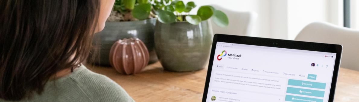 Vrouw bekijk de website van de Raadbaak op haar laptop. Ze zit aan tafel Vrouw bekijk de website van de Raadbaak op haar laptop. Ze zit aan tafel