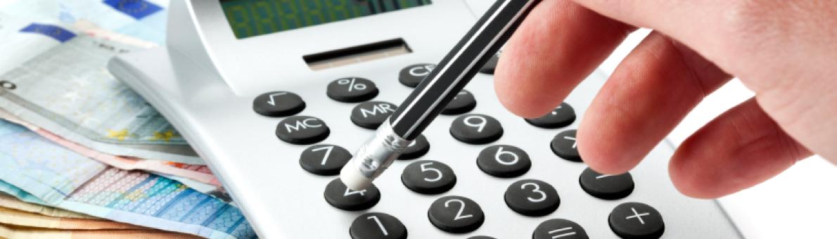 Foto van een rekenmachine op een stapel bankbiljetten en iemand die met een pen op de toetsen drukt