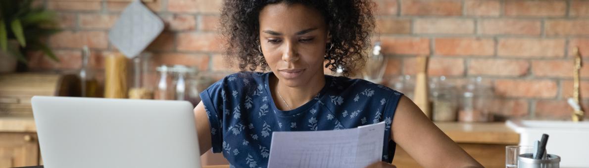 Vrouw zit aan keukentafel en neemt documenten door