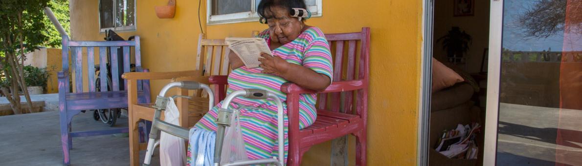 Oudere dame zit op bank van haar terras (Caribisch NL)