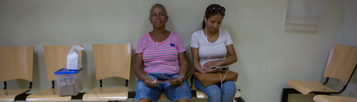 Twee vrouwen zitten op een bankje in de wachtkamer. De foto is genomen op Bonaire.