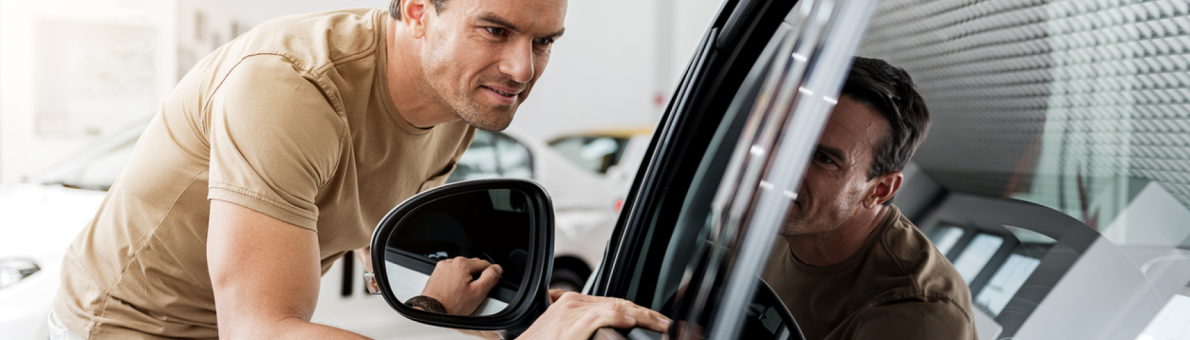 man staat voorovergebogen bij auto