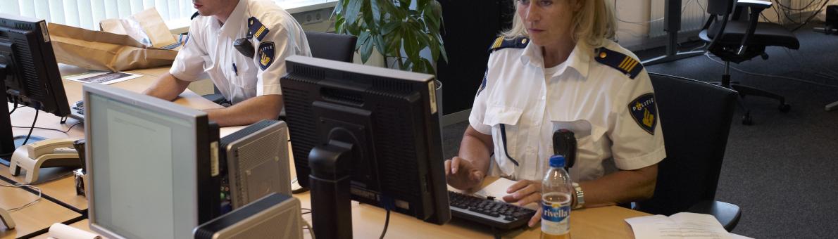 Foto van politieagenten achter een computer