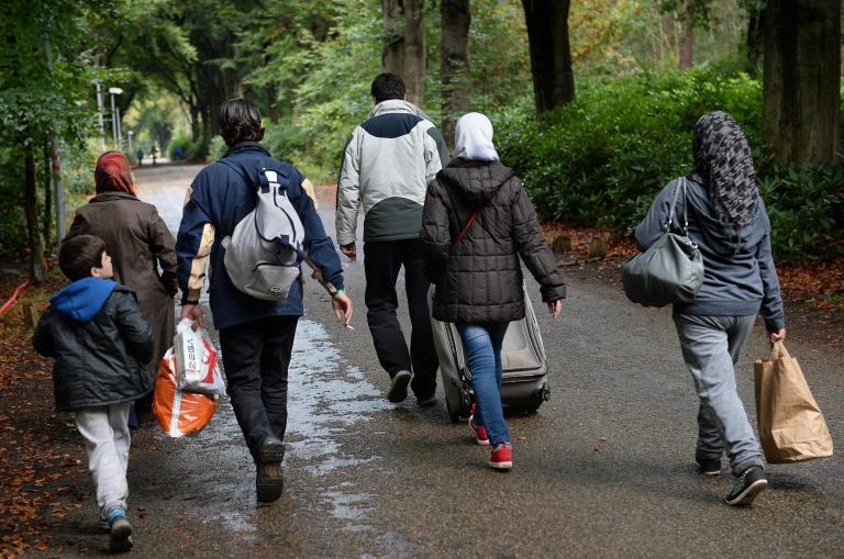 Asielzoekers lopen naar het Asielzoekerscentrum in Nijmegen