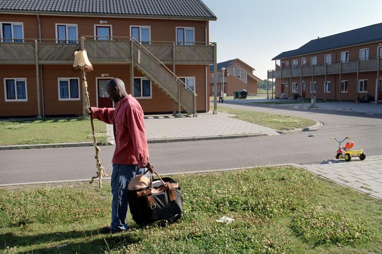 Man loopt over terrein van AZC met lamp in de hand