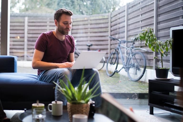 Man in kamer met laptop op schoot