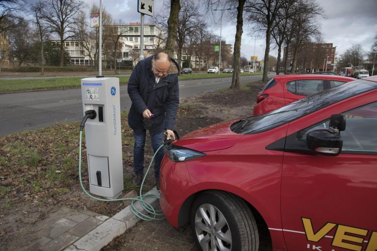 Man staat naast een elektrische laadpaal