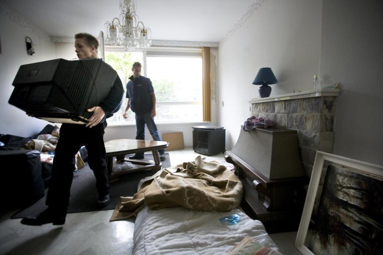 Mannen nemen spullen in beslag uit een woning