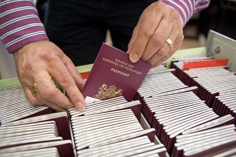 Man bladert door bak met Nederlandse paspoorten