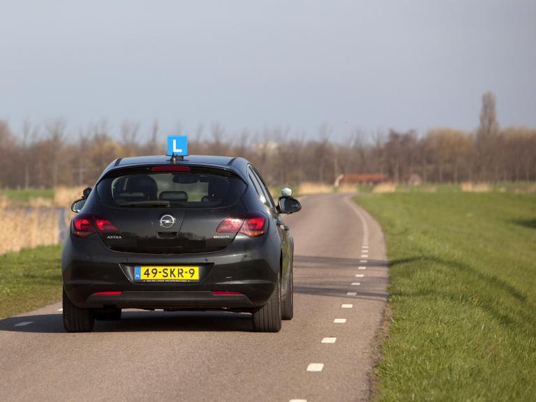 Zwarte rijles auto op de dijk