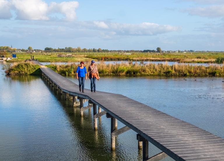 Twee mensen lopen door een Nederlands waterlandschap