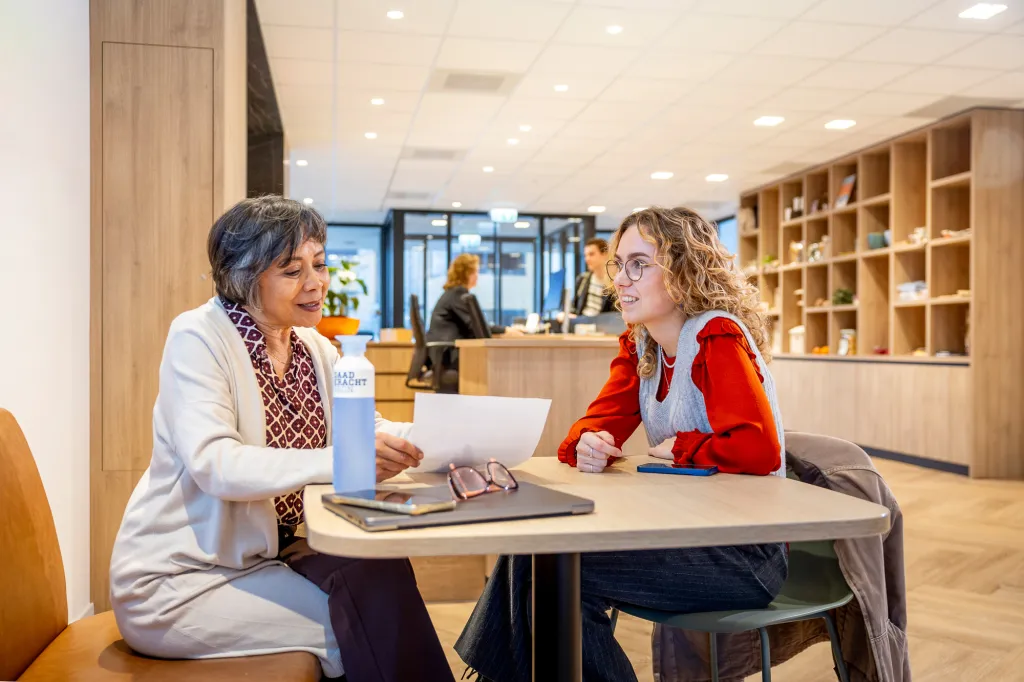 Vrouw praat met jongere vrouw aan een balie
