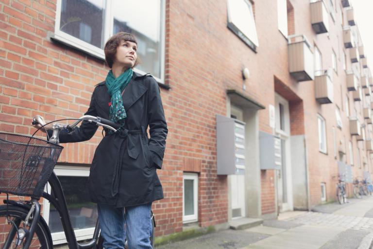 Vrouw staat met fiets voor haar huurflat