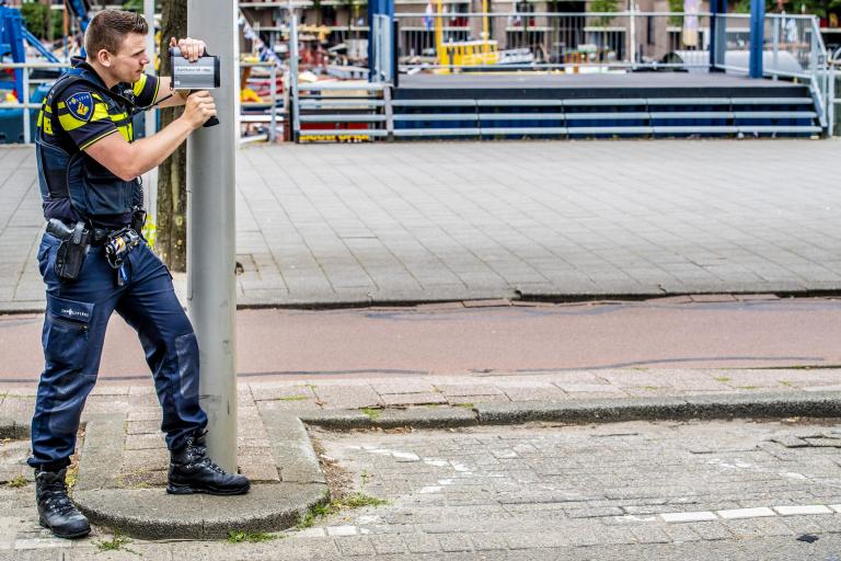 Politieagent meet snelheid verkeer. Het CJIB regelt dat boetes worden betaald.