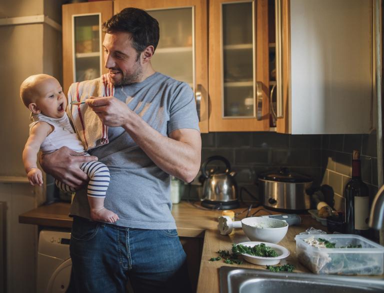 Man geeft baby te eten in keuken