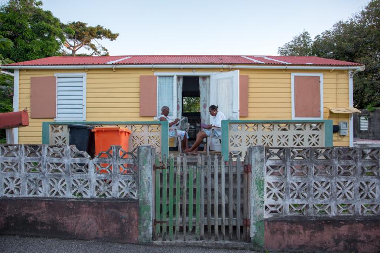 Twee mensen zitten voor hun huis op Statia